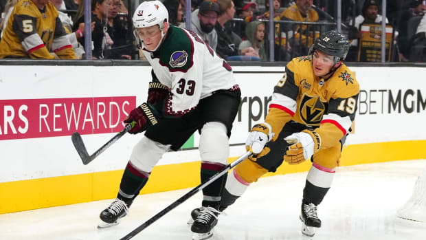 Coyotes defenseman Travis Dermott and Golden Knights center Brendan Brisson fight for a puck in a game.